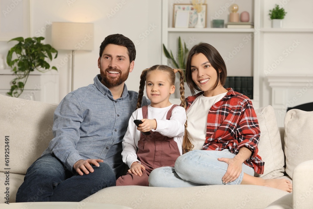 Happy family watching TV on sofa at home