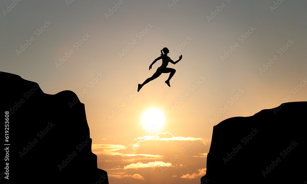 Concept of reaching life and business goals. Silhouette of woman jumping over chasm at sunrise
