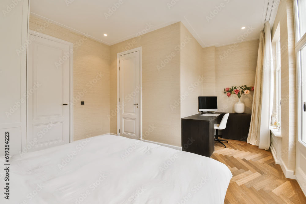 Fototapeta premium a bedroom with wood flooring and white sheets on the bed, there is a small desk in front of the window