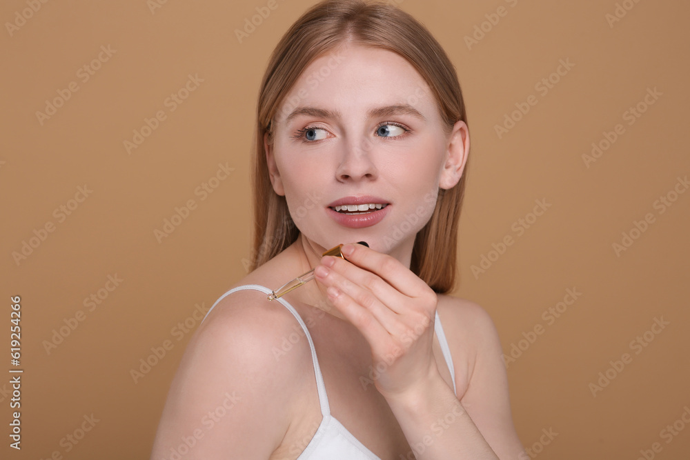 Beautiful young woman applying essential oil onto shoulder on brown background Beautiful young woman applying essential oil onto shoulder on brown background