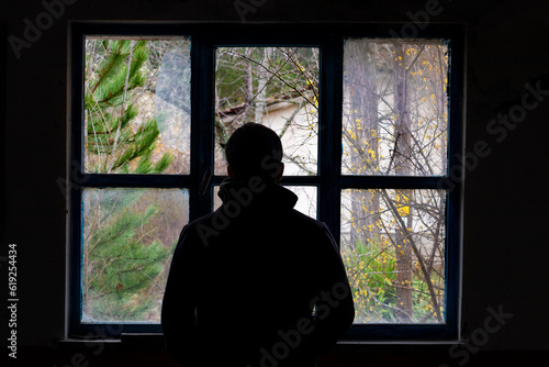 Silhouette of a man shot from behind in front of a shattered window