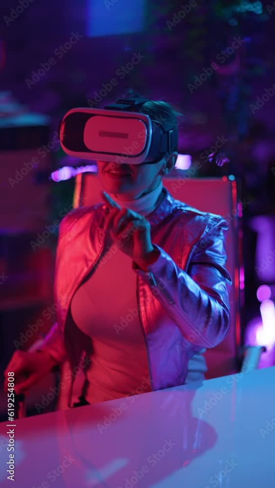 Neon metaverse futuristic concept. smiling modern middle aged woman in vr headset in modern office. Neon metaverse futuristic concept. smiling modern middle aged woman in vr headset in modern office.