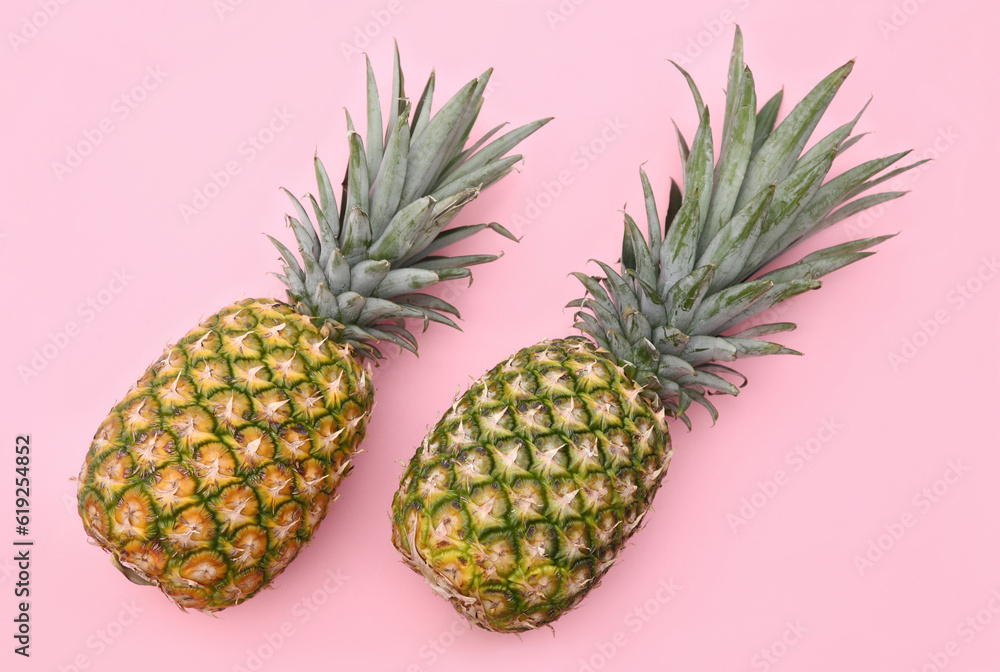 Fototapeta premium Delicious ripe pineapples on pink background, flat lay