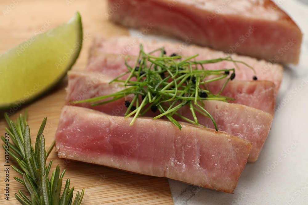 Pieces of delicious tuna steak with microgreens and rosemary on board, closeup Pieces of delicious tuna steak with microgreens and rosemary on board, closeup