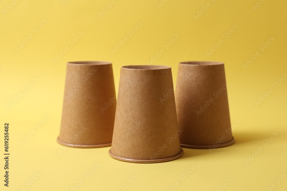 Three paper cups on yellow background. Thimblerig game Three paper cups on yellow background. Thimblerig game