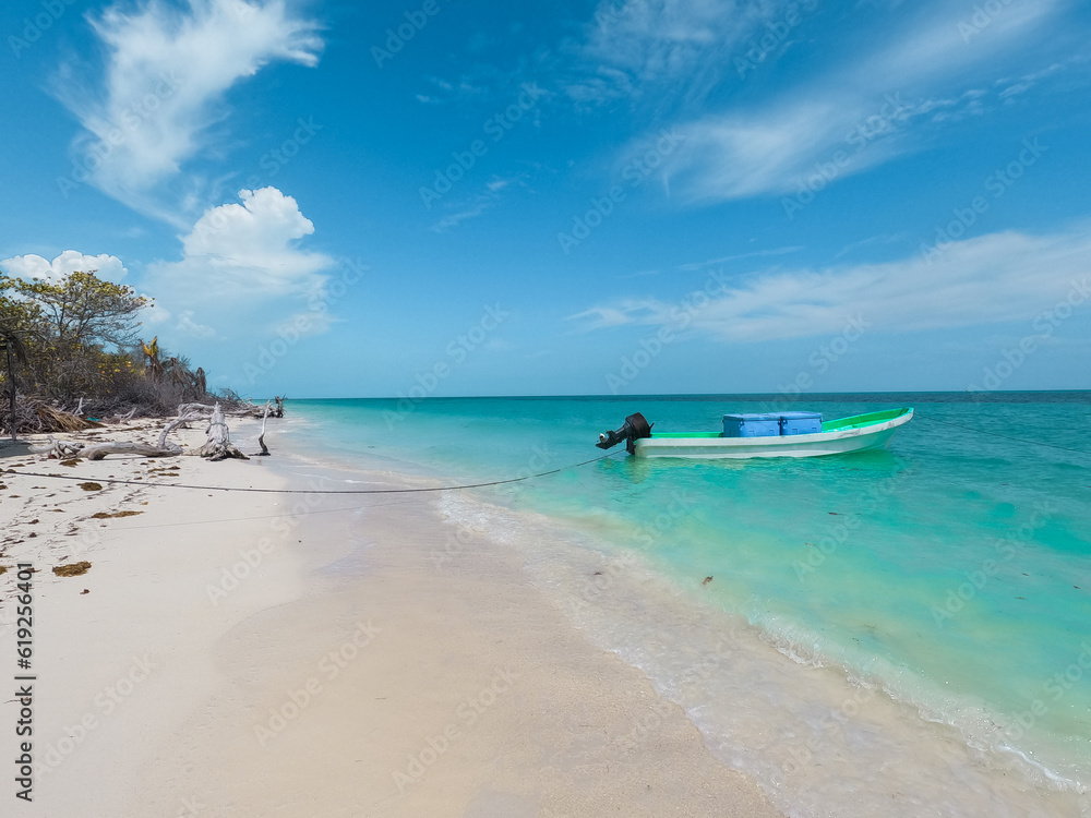 View of the coast of Cabo Catoche and a boat floating in the crystal clear waters of Holbox