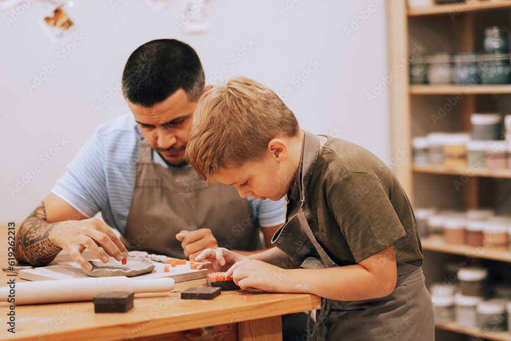 Dad and son are engaged in creativity in the pottery workshop. Dad and son are engaged in creativity in the pottery workshop.