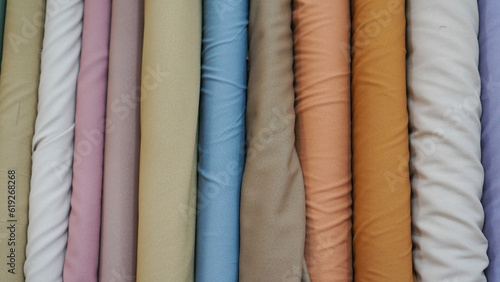 various types of rolled colorful fabrics with plain colors neatly arranged for the background 