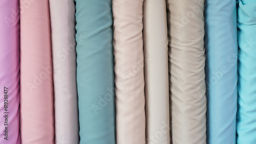 various types of rolled colorful fabrics with plain colors neatly arranged for the background 