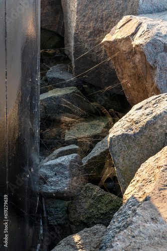 Fototapeta Naklejka Na Ścianę i Meble -  Rocks with spiderweb next to metal constriction 