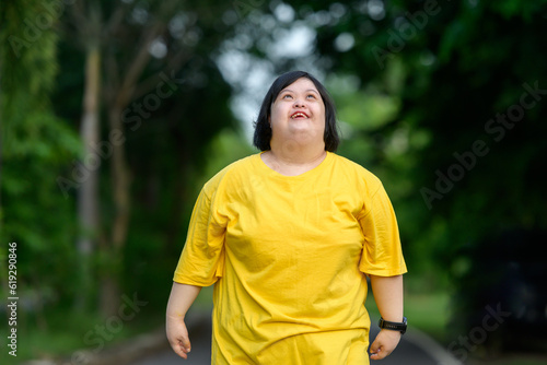 Asian woman with down syndrome smiling happy Fat young woman with down syndrome exercising in the park in the middle of nature
