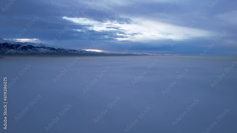 Flying a drone among the clouds with a view of the mountains. The light yellow rays of the sun at sunset are reflected on the surface of the clouds. Double layer of clouds. Mountains are visible Flying a drone among the clouds with a view of the mountains. The light yellow rays of the sun at sunset are reflected on the surface of the clouds. Double layer of clouds. Mountains are visible