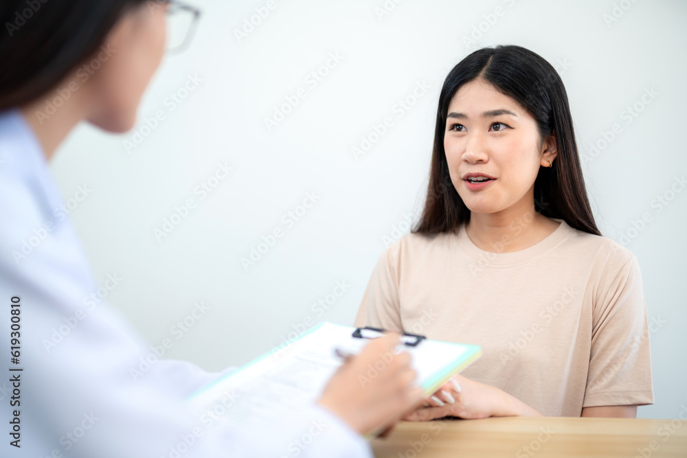 Asian female client or patient giving thanks to female doctor at ball hospital after getting treatment and medical advice. Asian female client or patient giving thanks to female doctor at ball hospital after getting treatment and medical advice.