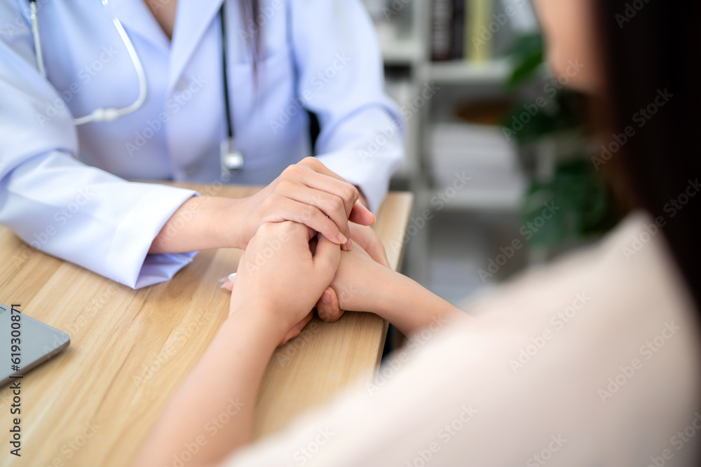Obraz premium Close up hand of doctor holding female patient's hand to encourage medical treatment and health care in the hospital office.