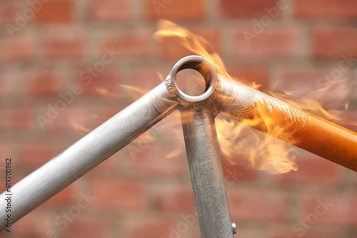 Manual bicycle renovation work, paint removal process using a blowtorch fire to change the color of a bike frame. Close up view. photo