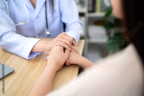 Close up hand of doctor holding female patient's hand to encourage medical treatment and health care in the hospital office.