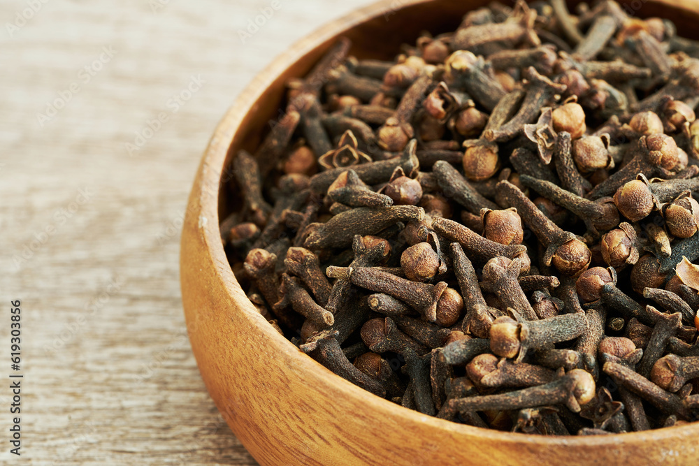 Obraz premium dry clove spice in wood bowl on table background. dry clove spice background. pile of dry clove spice in wood bowl food table background 