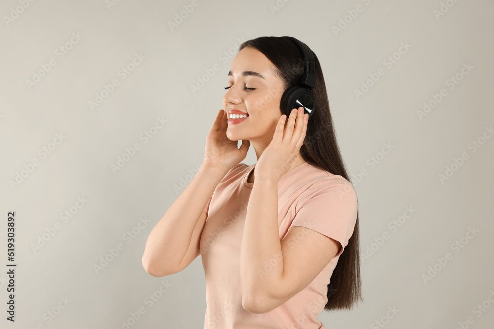 Happy woman in headphones enjoying music on grey background Happy woman in headphones enjoying music on grey background