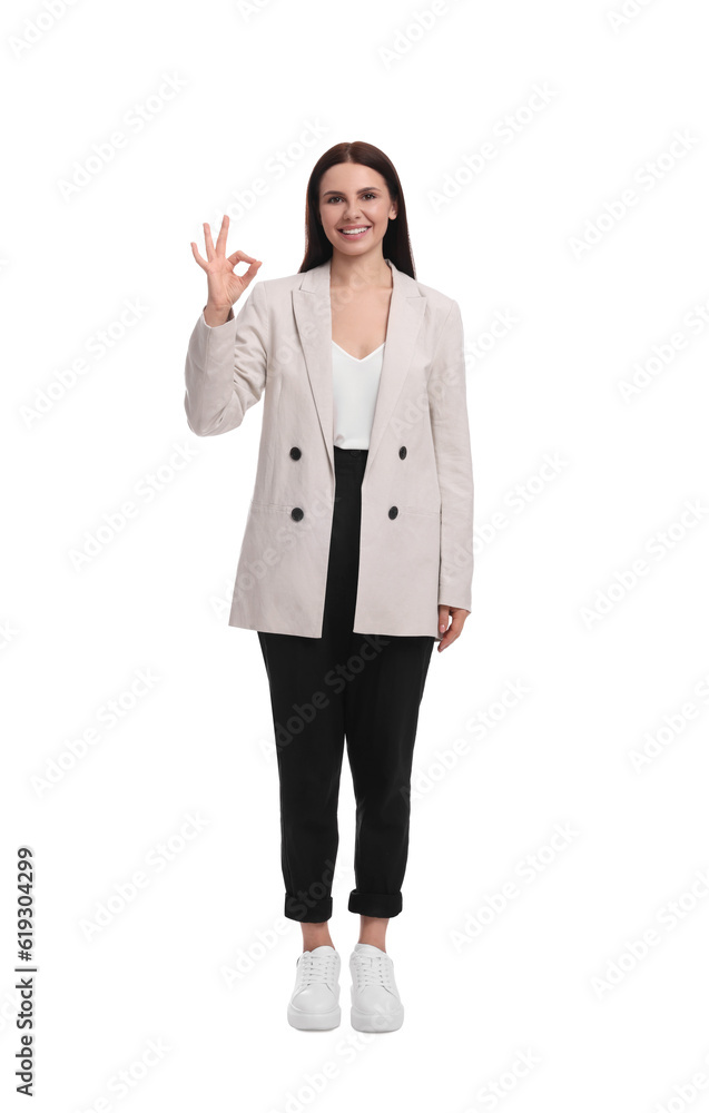 Beautiful businesswoman in suit showing OK gesture on white background Beautiful businesswoman in suit showing OK gesture on white background