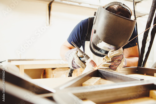 Male in face mask welds with argon-arc welding photo