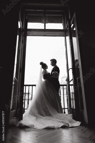 The first meeting of the groom in a black suit and the bride in a white wedding dress with a bouquet in the interior of a photo studio on a white and black background