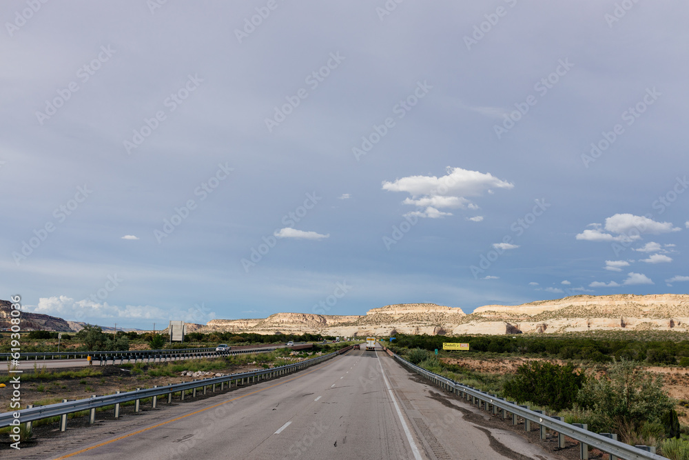 Beautiful highway in New Mexico, USA. Picturesque landscape with a road among mountains and dark blue sky on a sunny summer day. New Mexico, USA - 06-17-2023