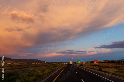 Scenic landscape with highway among mountains and colorful sky at dusk. Blue, orange and purple sky at sunset over the road. Highway 40, Arizona, USA - 06-17-2022 © Liudmila