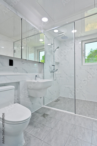 The shower space is separated with a glass partition in the bathroom decorated with Bianco tiles