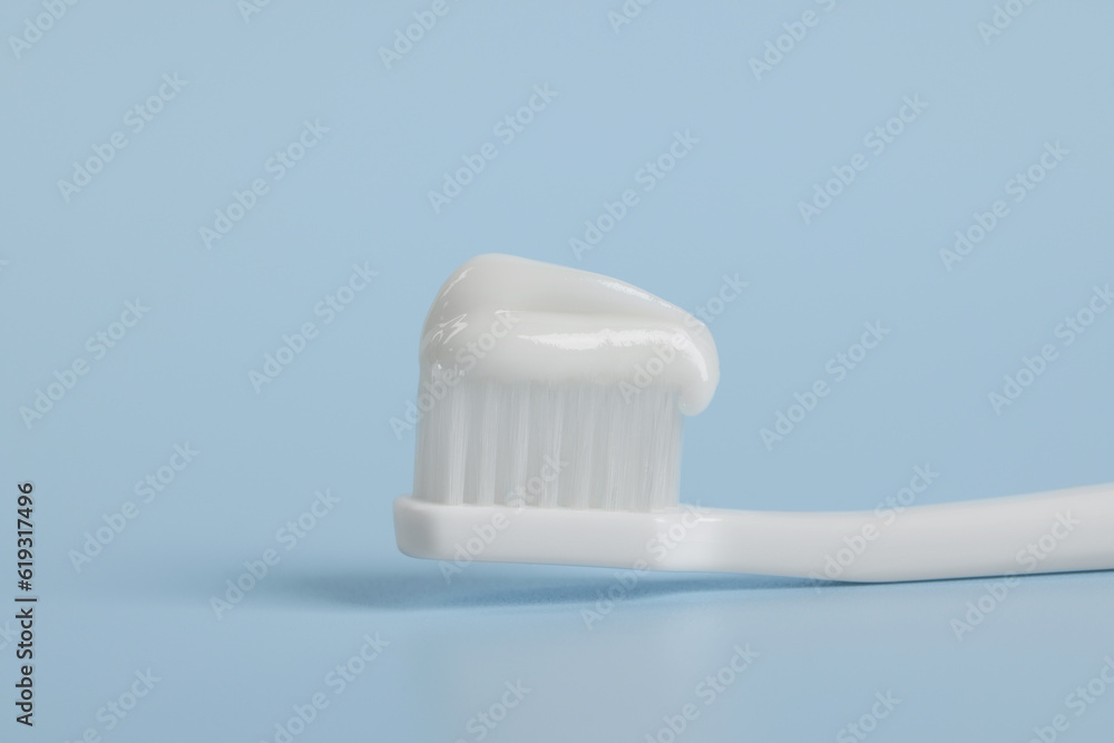Plastic toothbrush with paste on light blue background, closeup Plastic toothbrush with paste on light blue background, closeup