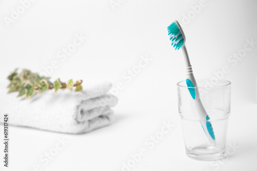 Light blue toothbrush in glass holder on white background  space for text