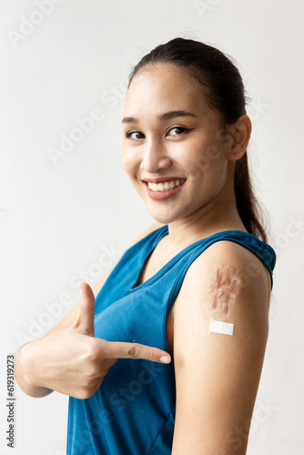 Billede på lærred Happy smiling healthy Asian Woman Receiving Vaccine Shot, pointing at Bandage on Injection Spot with large scar