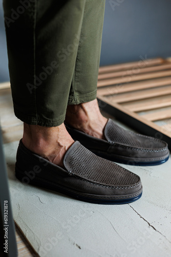 Male legs close-up in jeans and beige genuine leather moccasins.