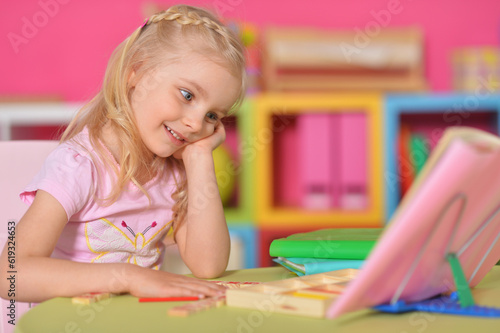 Little cute girl studying at the table at home