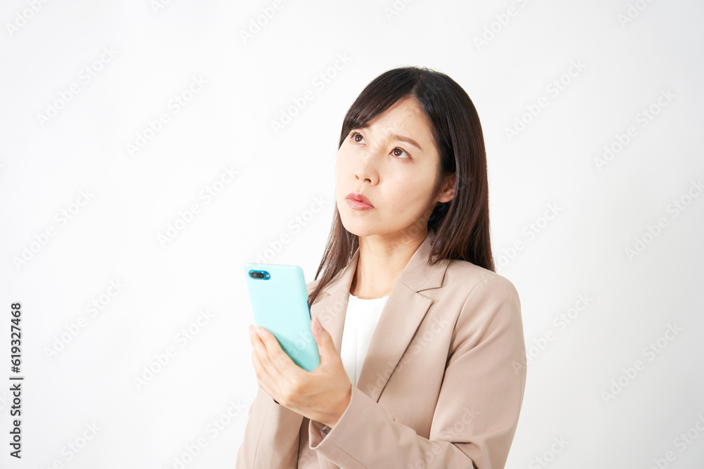 スマートフォンを持って考えるミドルエイジのビジネスウーマン 白背景 スマートフォンを持って考えるミドルエイジのビジネスウーマン 白背景