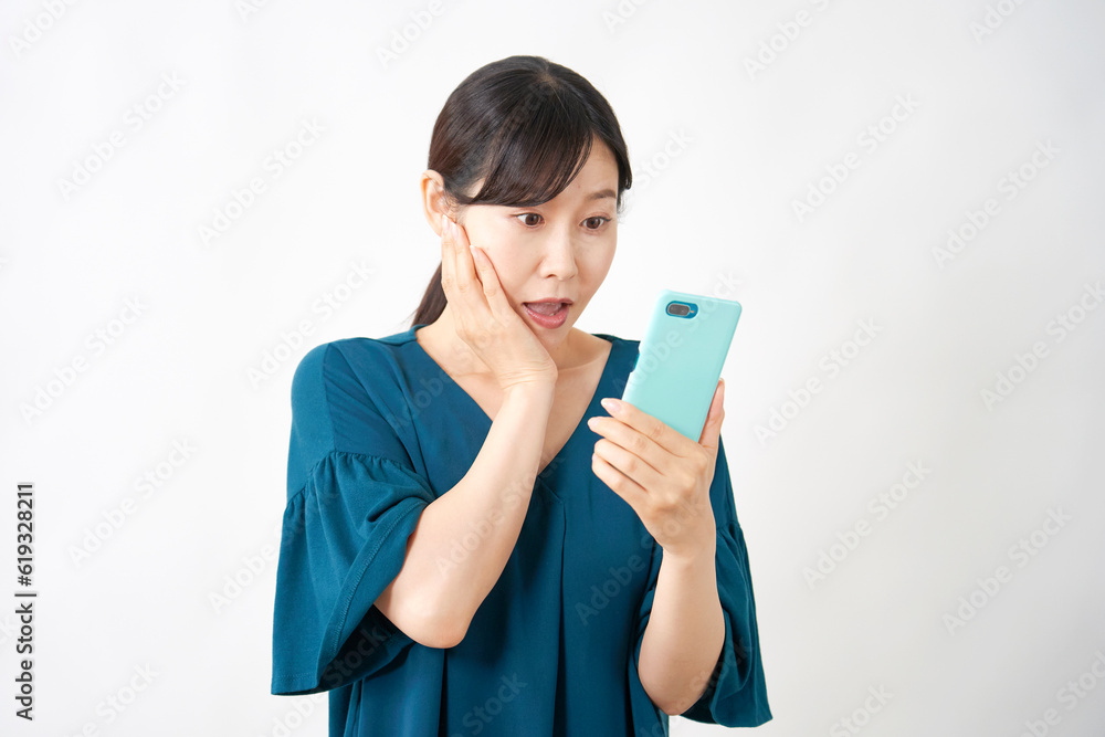 スマートフォンを持って驚くミドルエイジ女性 白背景 スマートフォンを持って驚くミドルエイジ女性 白背景