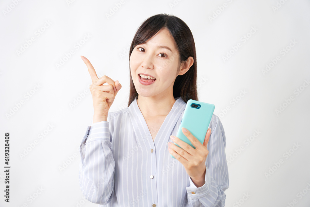 スマートフォンを持って左側を指差すミドルエイジ女性 白背景 スマートフォンを持って左側を指差すミドルエイジ女性 白背景