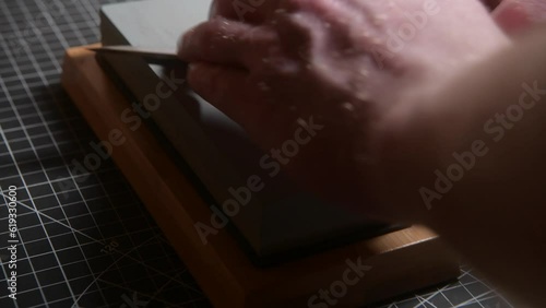 Sharpening a bushcraft knife to a razor edge on a whetstone. Close up shot photo