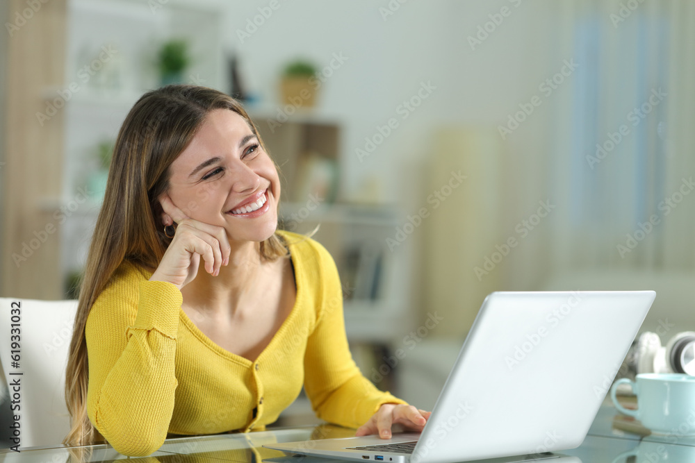 Obraz premium Happy woman at home dreaming with a laptop