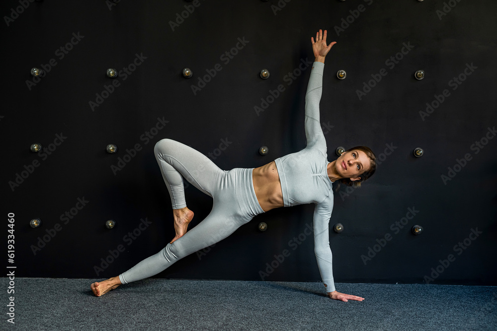 woman practicing yoga does an exercise in pose from yoga book and works out wearing sportswear.