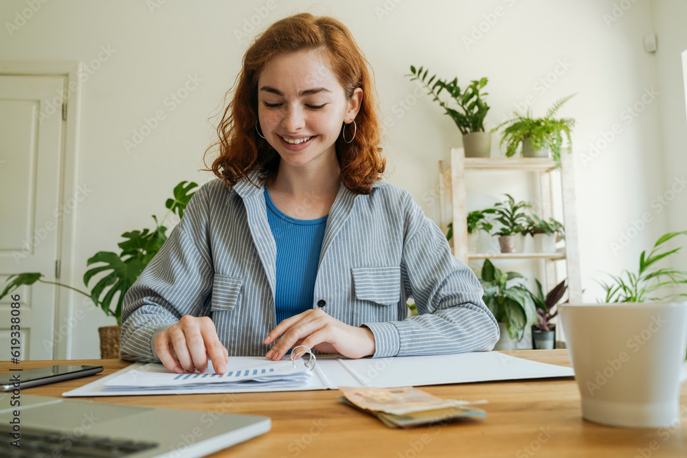 Happy young woman calculating financial graph at home Happy young woman calculating financial graph at home