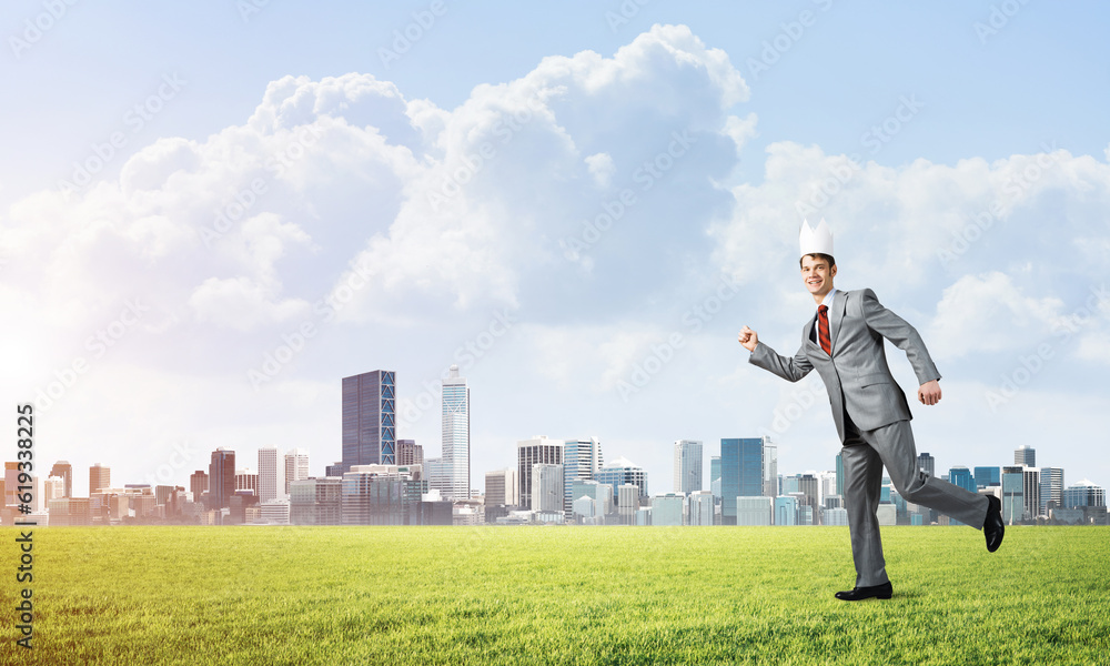 King businessman in elegant suit running on green grass and modern cityscape at background King businessman in elegant suit running on green grass and modern cityscape at background