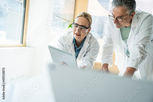 Scientists working with tablet computer in laboratory photo