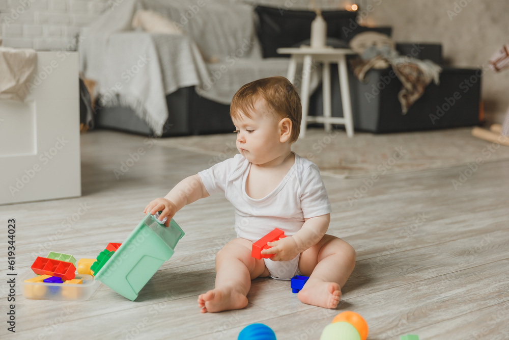 baby 6-9 months old playing with a colorful rainbow toy pyramid sitting in a white sunny bedroom. Toys for small children. Children's interior. A child with an educational toy. baby 6-9 months old playing with a colorful rainbow toy pyramid sitting in a white sunny bedroom. Toys for small children. Children's interior. A child with an educational toy.