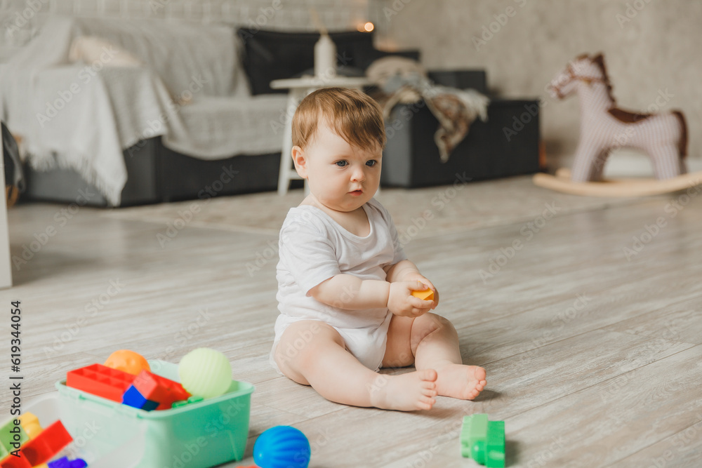 baby 6-9 months old playing with a colorful rainbow toy pyramid sitting in a white sunny bedroom. Toys for small children. Children's interior. A child with an educational toy. baby 6-9 months old playing with a colorful rainbow toy pyramid sitting in a white sunny bedroom. Toys for small children. Children's interior. A child with an educational toy.