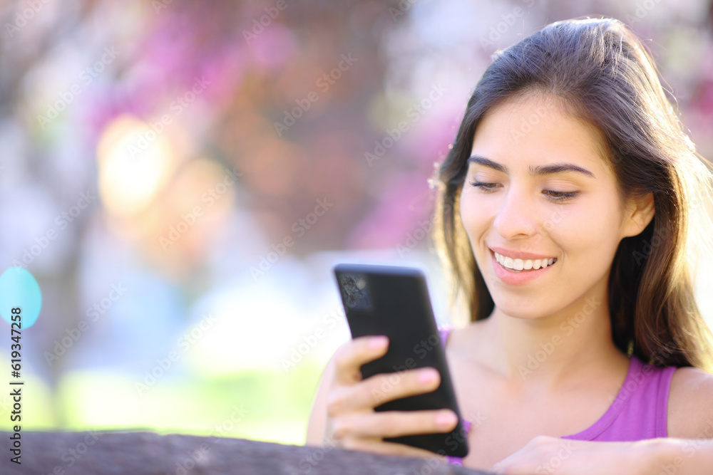 Happy woman using smart phone in a beautiful park Happy woman using smart phone in a beautiful park