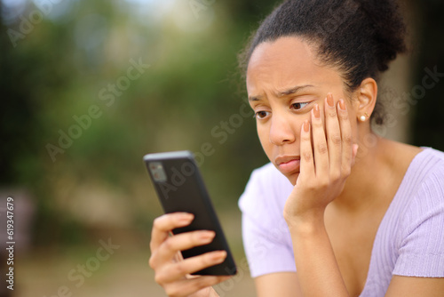 Fotografija Worried black female checking cell phone