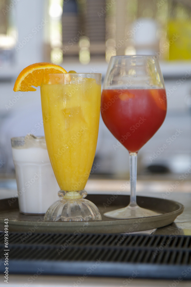 Glasses of aperol spritz and fresh squeezed orange juice on the bar counter, summer drinks for refreshment Glasses of aperol spritz and fresh squeezed orange juice on the bar counter, summer drinks for refreshment