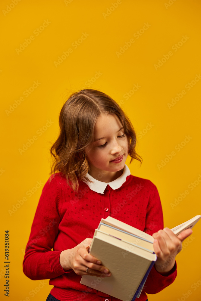 Portrait of happy schoolgirl reading a book on yellow studio Portrait of happy schoolgirl reading a book on yellow studio