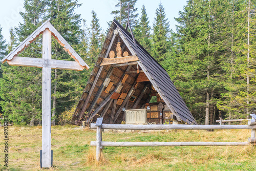 Chapel of Our Lady Protecting Tourists (with this name engraved on the beam) with a wooden cross standing next to it and a shepherd-type fence under the Okrąglica peak in the Beskid Żywiecki (Poland) photo