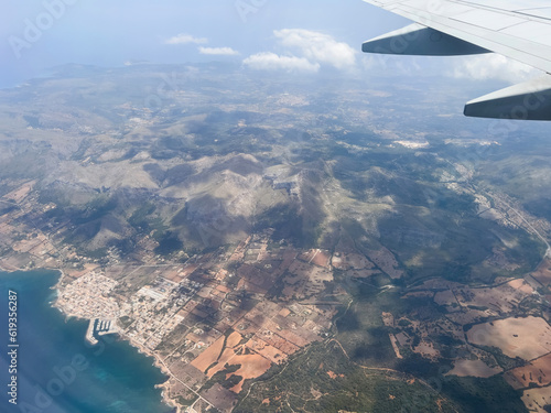 Above Mallorca, an aerial view reveals a serene landscape through an airplane window. Capturing land, water, and clouds, this scenic image embodies travel and transportation. photo